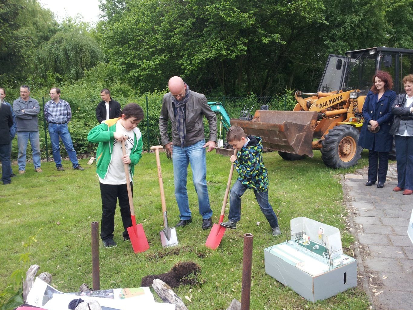 Halles Oberbürgermeister Bernd Wiegand und zwei Schüler der Grundschule Büschdorf setzen den ersten Spatenstich für den neuen Sportplatz.