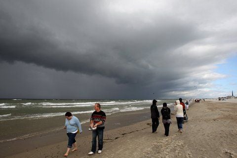Spaziergänger sind am Ostseestrand von Warnemünde unterwegs, dunkle Wolken sorgen für eine dramatische Kulisse (FOTO: DPA)