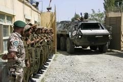 Ein deutscher und mehrere afghanische Soldaten stehen im Lager der deutschen ISAF-Truppe, während ein Panzerwagen vom Typ «Fuchs» der Sanitäter das Tor passiert. (Foto: dpa)
