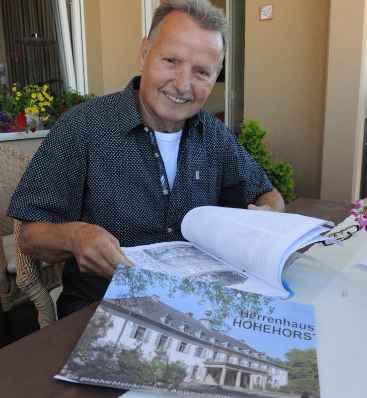 Gerhard Lindau auf seinem Balkon mit den Unterlagen über seinen Geburtsort.