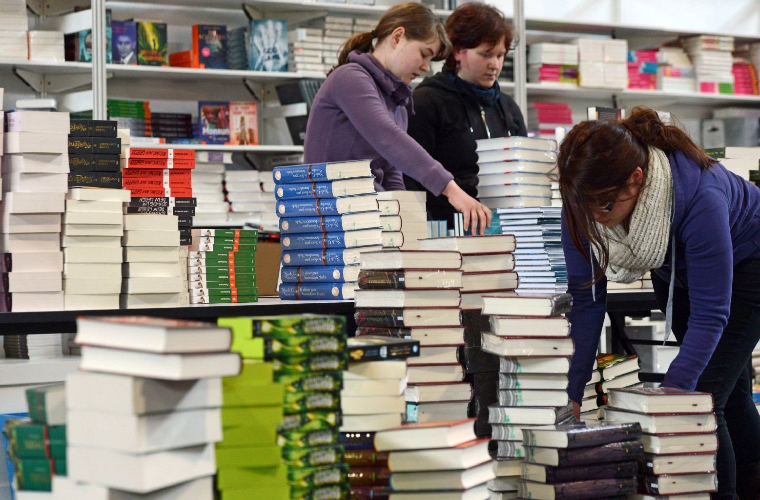 Mitarbeiterinnen einer Buchhandlung auf der Buchmesse Leipzig (Sachsen) sortieren am 13.03.2013 Bücher auf einen Stapel. Vom 14. bis 17. März präsentieren sich auf der Messe über 2000 Verlage aus 43 Ländern mit ihren Neuerscheinungen.