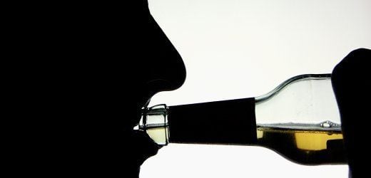 Die Silhouette eines Alkohol trinkenden jungen Mannes