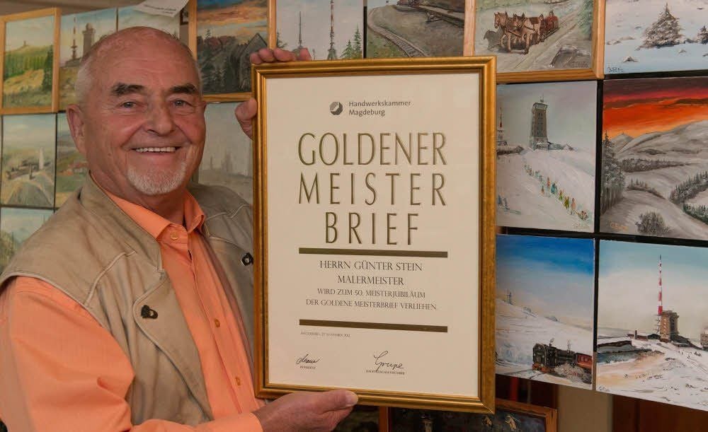 Stolz zeigt Günter Stein den Goldenen Meisterbrief - vor einigen der selbst gemalten Bilder.