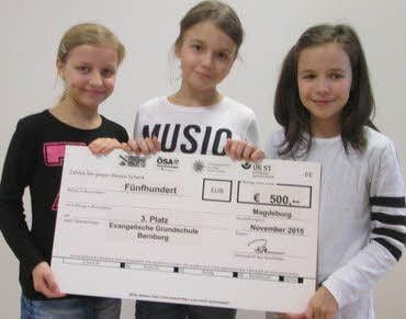 Schüler der evangelischen Grundschule aus dem Martinszentrum Bernburg halten den symbolischen Scheck für das Preisgeld.