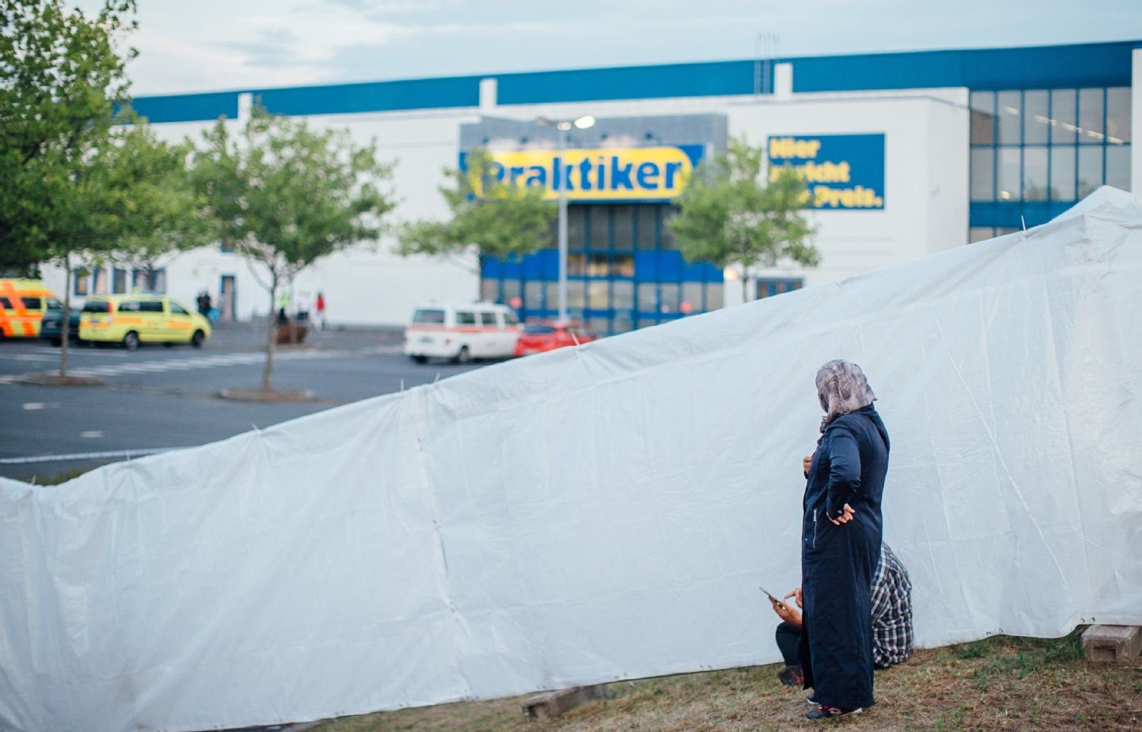 Ein Flüchtlingspaar schaut vor dem ehemaligen Praktiker-Baumarkt in Heidenau auf den Parkplatz.