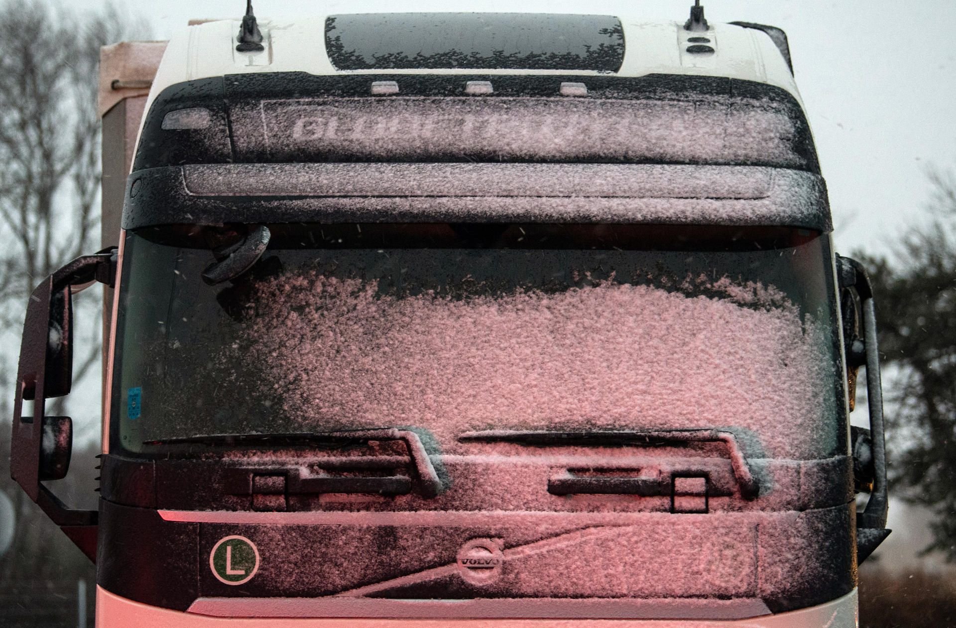 Schnee liegt auf der Frontscheibe eines Lastwagens auf einem Rastplatz der Autobahn.