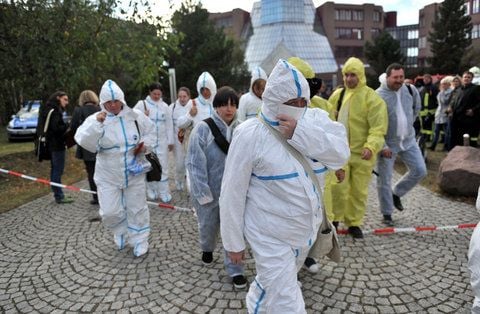 Mitarbeiter eines Standortes der Deutschen Bank in Schkeuditz (Sachsen) verlassen das Gebäude in Schutzanzügen. (FOTO: DPA)