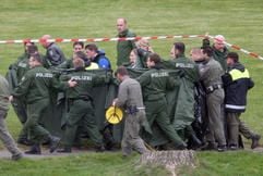 Mit Decken schirmen Polizisten am Donnerstag (19.10.2006) am Gederner See im Vogelsbergkreis zwei Polizeitaucher ab, die die Leiche des kleinen Marvin ans Ufer tragen. (Foto: dpa)