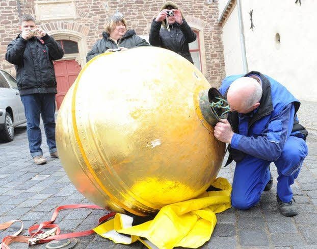 Der Kran bringt die Kugel sicher nach unten (links). Peter Rostalski angelt drei Kapseln mit Zeitdokumenten heraus.