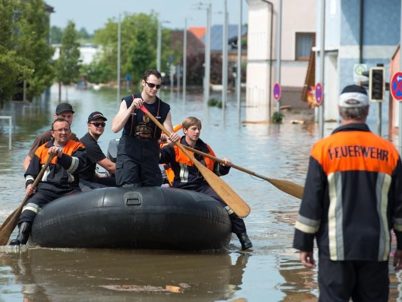 Rettungskräfte fahren mit einem Schlauchboot durch eine überflutete Straße: Arbeitgeber müssen Angestellten frei geben, die ehrenamtlich gegen das Hochwasser im Einsatz sind.