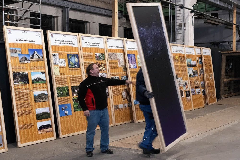 Die Ausstellungstafeln mit Fotos und Texten werden in der Halle verteilt.