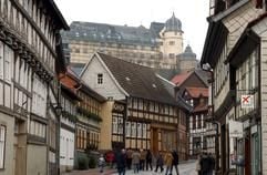 Touristen laufen durch das mittelalterliche Stadtzentrum des Harzstädtchens Stolberg, über dem sich das eingerüstete barocke Ensemle des Schlosses erhebt. (Foto: dpa)