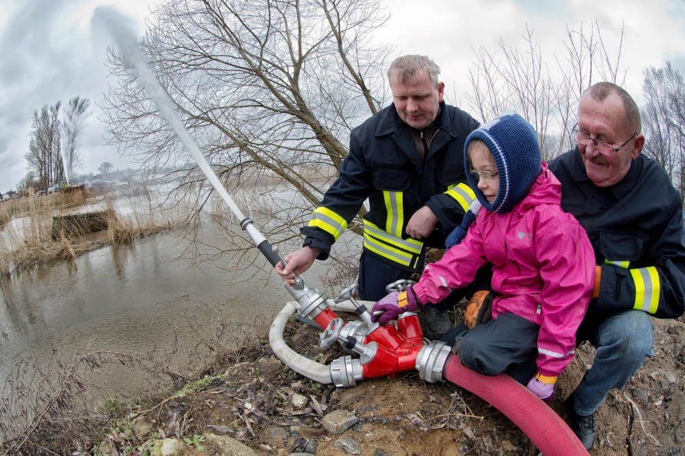 Auch Klossas Nachwuchs übt sich bereits im Brückenschlag an der Schwarzen Elster. Angeleitet von Wilfried Globig (links) und Michael Putensen öffnet Melina die Schleusen für den Wasserbogen über den Fluss.