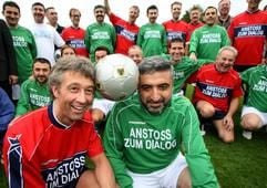Pfarrer Ralf Greth (l.) und der Imam Züfer Altas halten in Dortmund gemeinsam den Ball zwischen ihren Köpfen, hinter ihnen stehen ihre Mannschaftskameraden. (Foto: dpa)