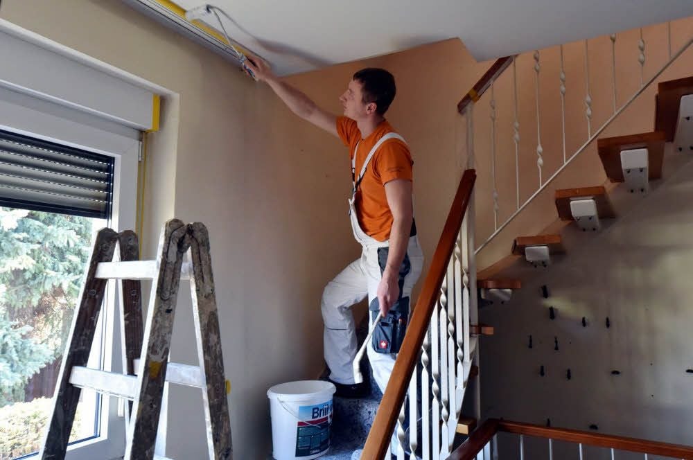 Sebastian Hofmann streicht den Treppenaufgang in einem Haus.
