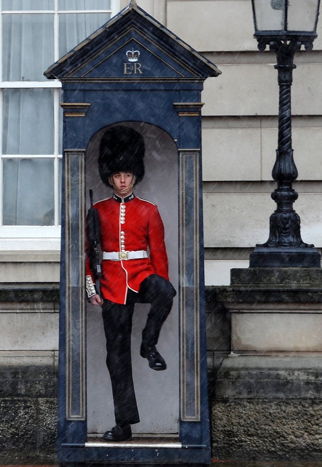 Ein Leibgardist steht in roter Sommeruniform vor dem Buckingham Palast in London.