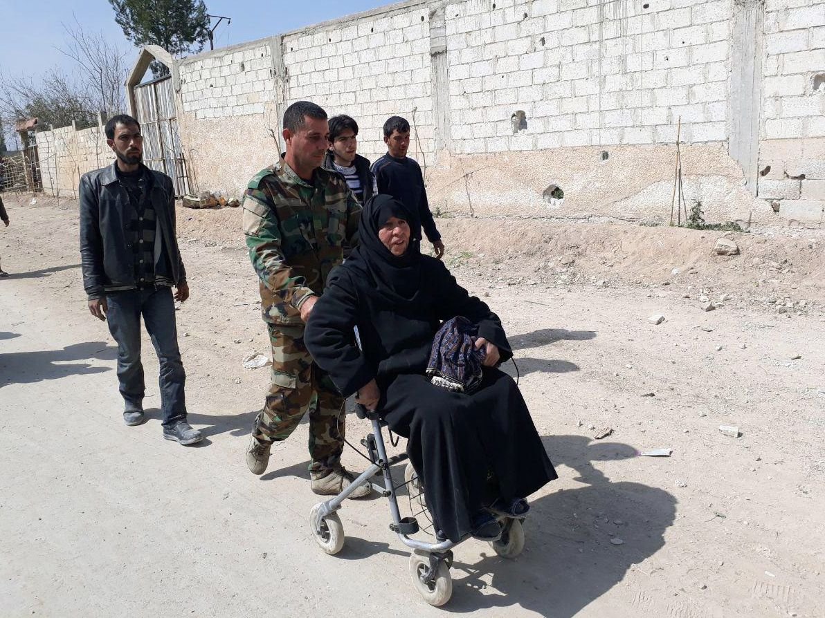 Ein Soldat der syrischen Armee hilft einer Frau, das umkämpfte Rebellengebiet Ost-Ghuta zu verlassen.