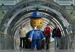 Drei Passanten gehen in der Glashalle der Neuen Messe in Leipzig am Messemännchen, dem früheren Maskottchen der Leipziger Messe, vorbei. (Archivbild vom 24.09.2003: dpa)