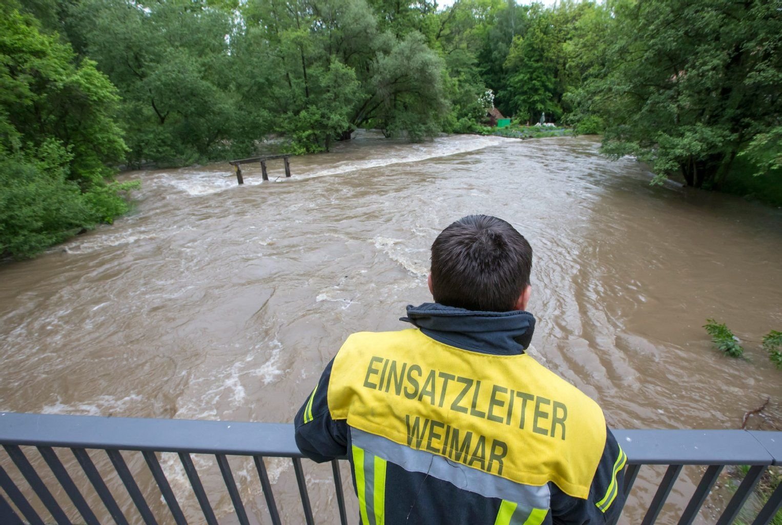 Ein Feuerwehrmann beobachtet am 27. Mai in Taubach (Thüringen) das Hochwasser an der über die Ufer getretenen Ilm. An vielen Flüssen steigen die Pegelstände nach Dauerregen.