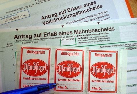Ein Stift zeigt auf Mahn- und Vollstreckungsbescheide sowie Pfandsiegel-Aufkleber. (ARCHIVFOTO: DPA)