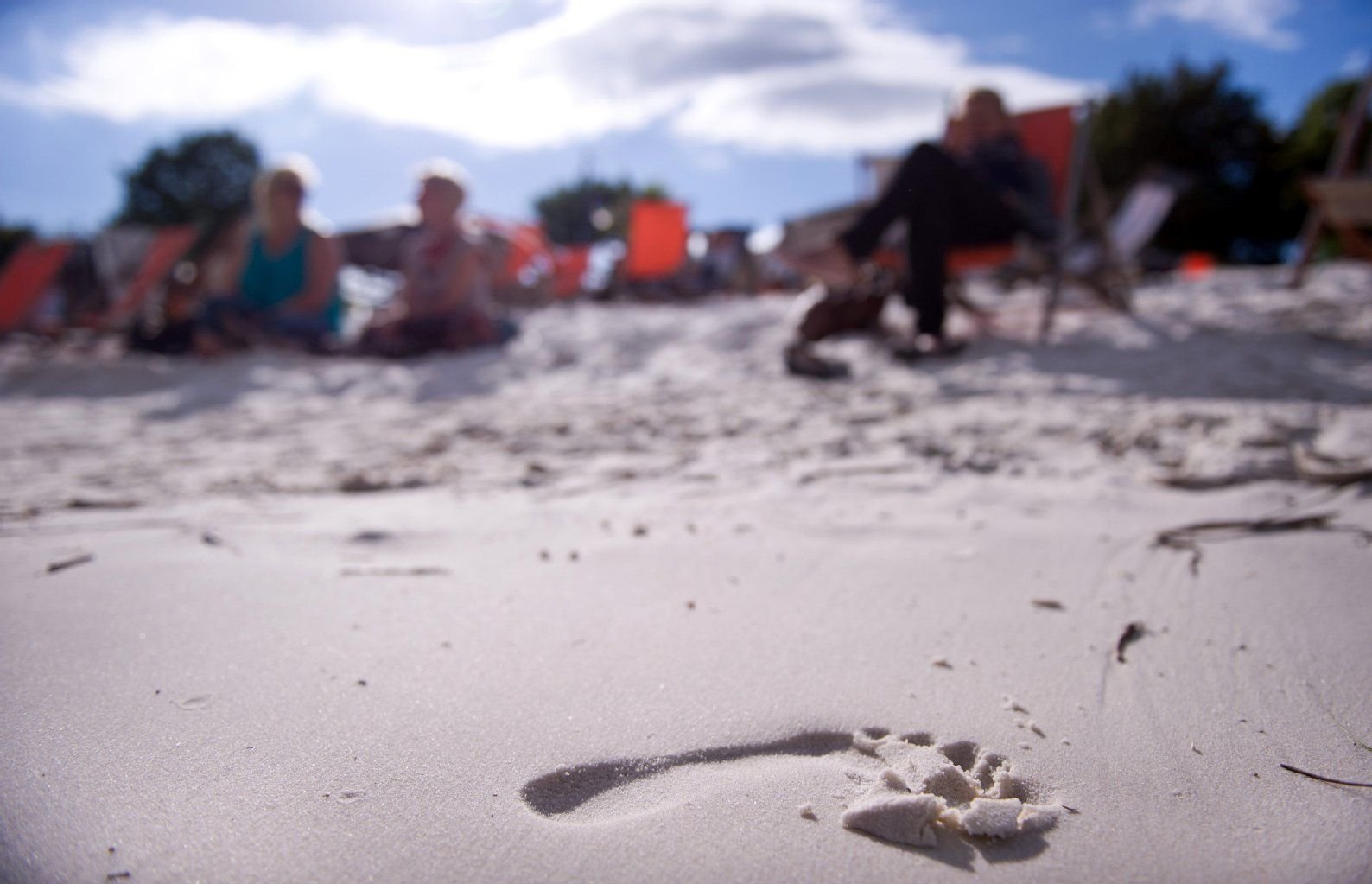 Ein Fußabdruck im weißen Sand ist vor Besuchern einer Strandbar an der Elbe in Magdeburg zu sehen. Der Sommer in Mitteldeutschland könnte nach den aktuellen Wettermodellen warm und trocken ausfallen.