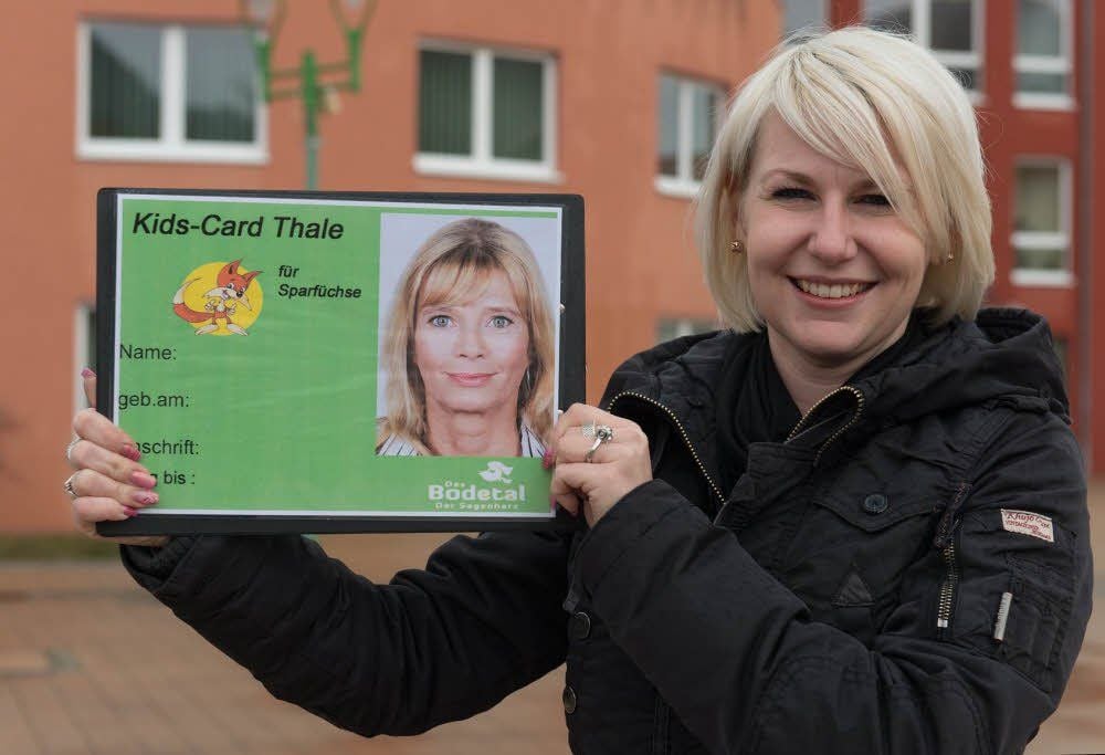 Verwaltungsmitarbeiterin Sina Meisel zeigt hier die Kids-Card vor dem Rathaus der Stadt.