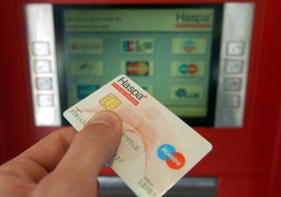 Ein Kunde will in einer Filiale der Hamburger Sparkasse mit seiner Bankkarte Geld abheben. (Foto: dpa)