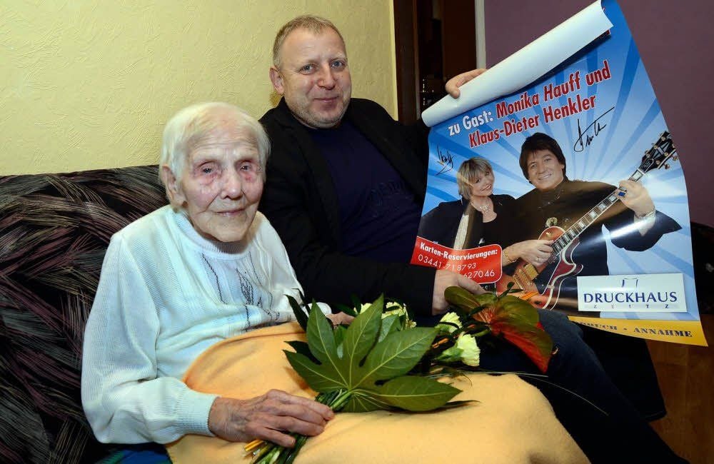 Frieda Mirre aus Bergisdorf feierte am Montag ihren 104. Geburtstag. Bürgermeister Uwe Kraneis gratuliert und schenkt ihr ein Plakat mit den Original-Unterschriften von Schlagerstar Hauff & Henkler.