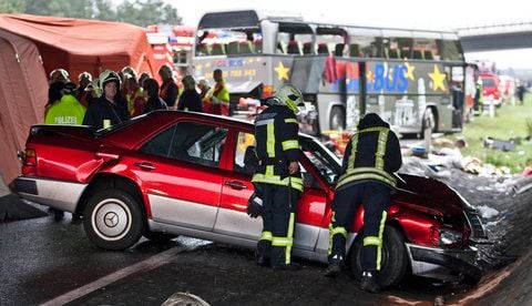 Sanitäter und Einsatzkräfte der Feuerwehr stehen am Schönefelder Kreuz bei Berlin neben den Wracks eines verunfallten Pkw (vorn) und eines Reisebusses (hinten). (FOTO: DAPD)