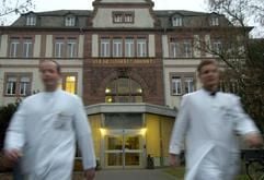 Mit wehenden Kitteln verlassen zwei Ärzte am Dienstag (14.12.2004) die alte Chirurgie der Uniklinik Gießen. Hessen verkauft bundesweit erstmals zwei komplette Universitätskliniken. Ministerpräsident Koch (CDU) sagte am Dienstag im Landtag, die Kliniken im mittelhessischen Gießen und Marburg mit zusammen knapp 10 500 Arbeitsplätzen würden 2005 zu einer gemeinsamen Anstalt öffentlichen Rechts zusammengeführt und zum 1. Januar 2006 privatisiert. Für die Mitarbeiter gelte dabei eine Beschäftigungsgarantie bis 31.12. 2010. (Foto: dpa)