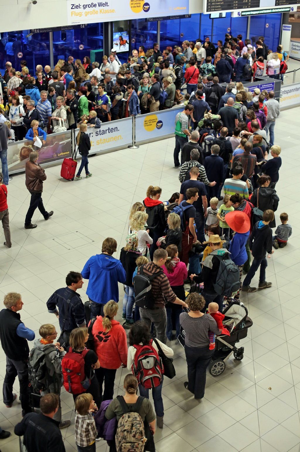 Flugreisende warten in einer Schlange vor der Sicherheitskontrolle auf dem Flughafen Leipzig/Halle.