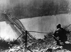 Ein amerikanischer Soldat blickt im Zweiten Weltkrieg auf die Brücke von Remagen (undatiertes Archivfoto). Für US-Amerikaner zählt die Ruine der Rhein-Brücke zwischen Bonn und Koblenz zu den Sehenswürdigkeiten in Deutschland. Denn hier geschah vor 60 Jahren kurz vor Ende des Zweiten Weltkrieges etwas, womit keiner gerechnet hatte. Alliierte Truppen konnten erstmals den Rhein in Richtung Osten über eine noch stehende Brücke überqueren. Einige Historiker glauben, dass dadurch der Zweite Weltkrieg verkürzt wurde. Die Wehrmacht hatte vergeblich versucht, das Bauwerk zu zerstören. Heute erinnert ein Museum in den linksrheinischen Brückentürmen an die dramatischen Stunden. (Foto: dpa)