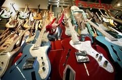 Model Angie testet am Dienstag (05.04.2005) auf der Frankfurter Musikmesse am Stand des US-amerikanischen Giterrenherstellers Fender eine E-Gitarre. Umgeben ist sie von lauter Einzelstücken, die bis zu 20.000 Euro kosten können. Die internationale Musikmesse Frankfurt, die vom 6. bis zum 9. April stattfindet, ist die größte Fachmesse für Musikinstrumente, Musiksoftware und Computerhardware und Noten. (Foto: dpa)