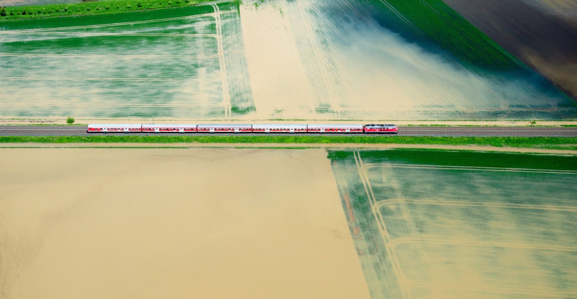 Ein Regionalzug der Deutschen Bahn fährt im Mai 2013 bei Hildesheim zwischen vom Hochwasser überfluteten Feldern entlang.