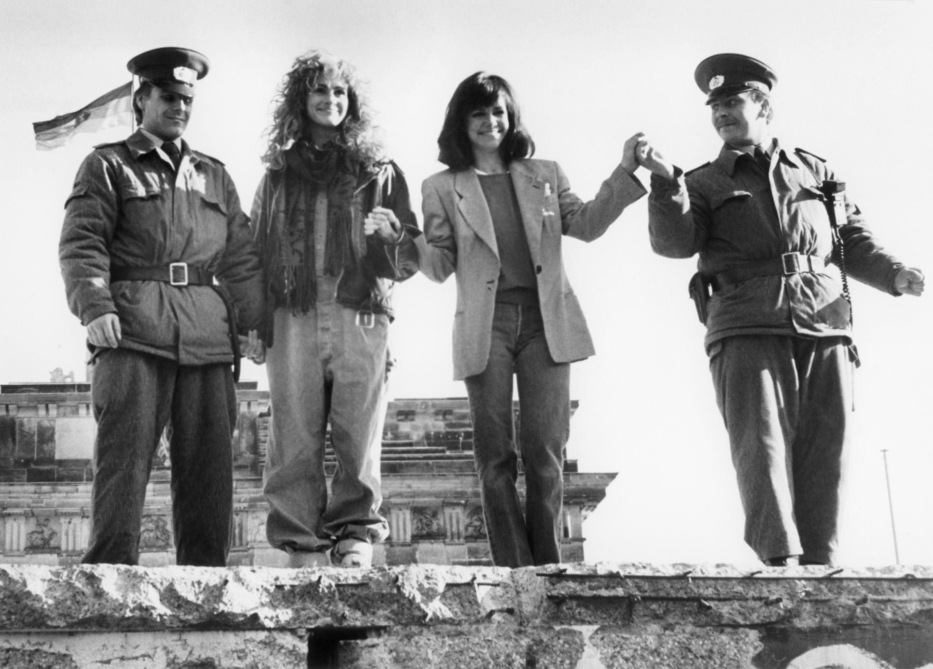 Die amerikanischen Schauspielerinnen Julia Roberts (l) und Sally Field stehen in Berlin mit zwei DDR-Grenzposten auf der Berliner Mauer am Brandenburger Tor.