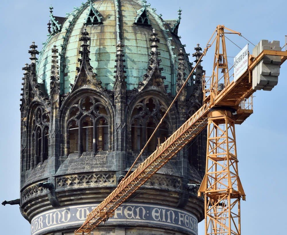 Ein Kran steht auf einer Baustelle neben der Kuppel des Turmes der Schlosskirche in Wittenberg.