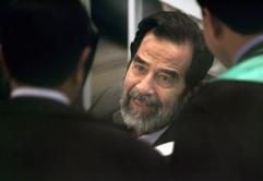 Der frühere irakische Diktator Saddam Hussein im Gespräch mit seinen Verteidigern zu Beginn seines Prozesses. Hussein muss sich seit Mittwoch (19. Oktober 2005) wegen Verbrechen gegen die Menschlichkeit verantworten. (Foto: dpa)