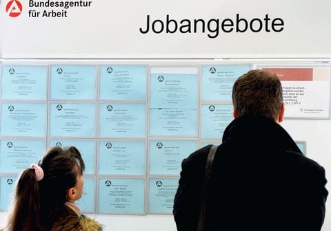 Bewerber suchen an einer Informationstafel nach offenen Stellen. (FOTO: DPA)
