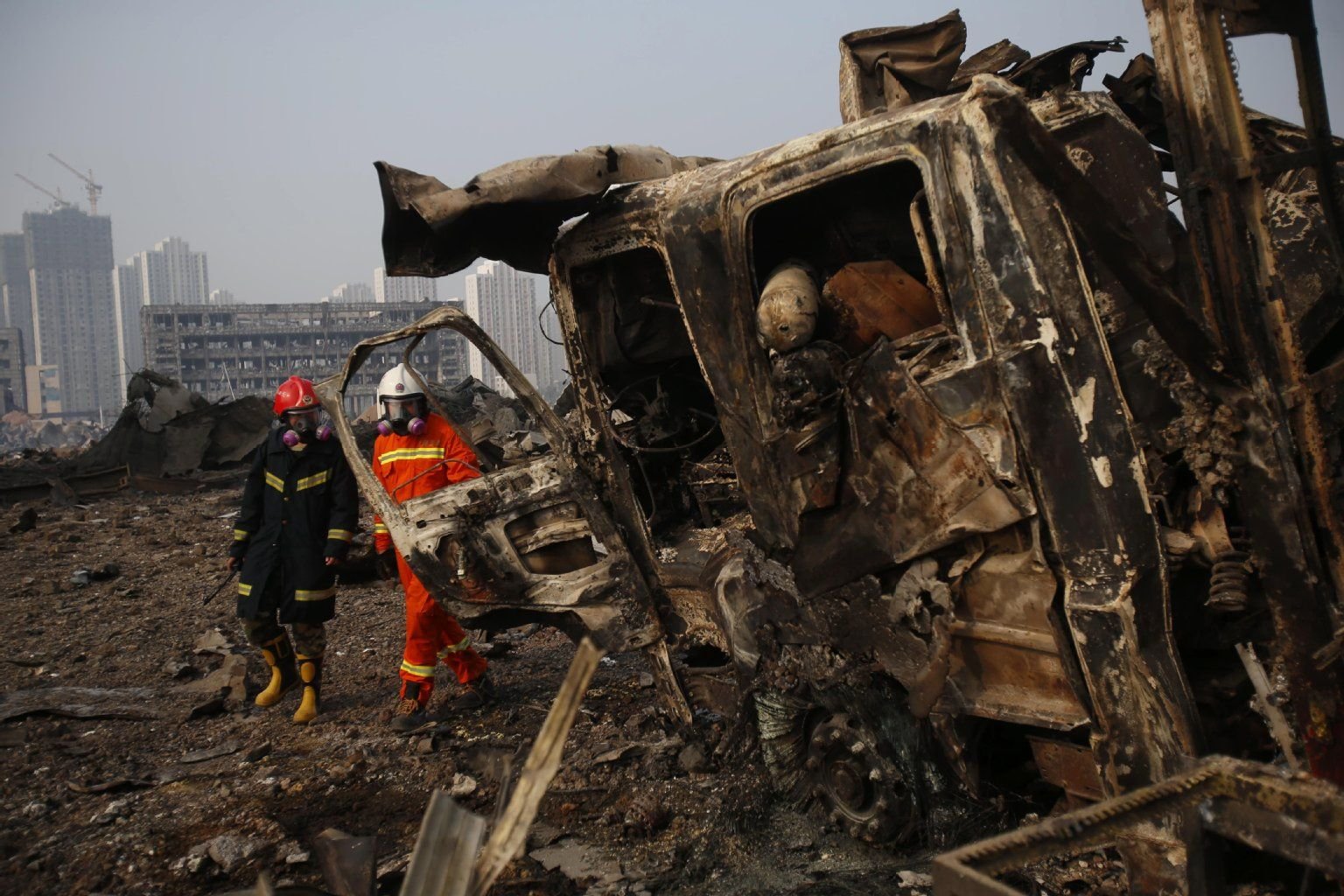 Feuerwehrleute blicken auf einen komplett zerstörten LKW.