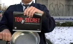 Vor der Zentrale des Bundesnachrichtendienstes in Pullach bei München zeigt am Montag (20.01.2003) ein Mitarbeiter das erste Kochbuch der Behörde. Unter dem Titel "Top(f) Secret" ist in zwei Dutzend Rezepte aus den verschiedensten Einsatzgebieten der Geheimdienstler beschrieben, was dort so in die Pfanne gehauen wird. (Foto: dpa)