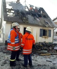 Rettungskräfte stehen am Samstag (29.01.2005) in Hoßkirch (Landkreis Ravensburg) vor einem ausgebrannten Einfamilienhaus. Bei dem Feuer starben drei Kinder und eine 32-jährige Frau. Die Brandursache ist noch unbekannt. (Foto: dpa)