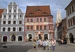 Touristen gehen in der Görlitzer Altstadt über den Untermarkt, im Hintergrund ist die alte Ratsapotheke von 1558 zu sehen und rechts im Hintergrund erblickt man die Türme der Peterskirche. (Foto: dpa)