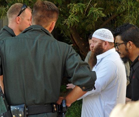 Der Leipziger Imam Hassan Dabbagh steht in Leipzig Mockau hinter einer Polizeiabsperrung. (FOTO: DPA)