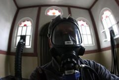 Ein Besucher mit einer umluftunabhängigen Schutzmaske steht am Samstag (11.03.2006) während der Pressevorbesichtigung der Kunstaktion 245 Kubikmeter Autoabgase in der Synagoge in Stommeln. (Foto: dpa)
