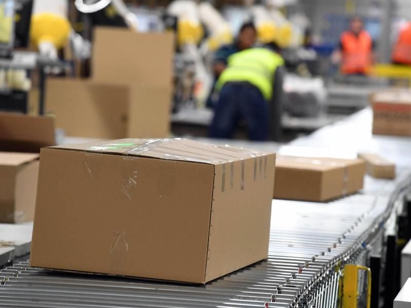 In einem Amazon Logistikzentrum laufen Pakete auf einem Band zum Versand. Foto: Uli Deck/Illustration
