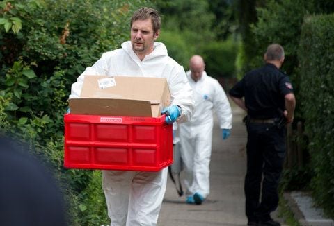 Ein Ermittler in weißem Anzug trägt am Freitag in Groß Ilsede bei Peine eine rote Kiste und einen Platiksack aus dem Reihenhaus, in dem vier Kinder zu Tode kamen. (FOTO: DPA)