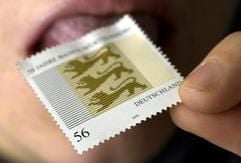 Eine Briefmarke wird mit der Zunge angeleckt. Die Deutsche Post hält ihre Preise im Inland 2006 weitgehend konstant. (Foto: dpa)
