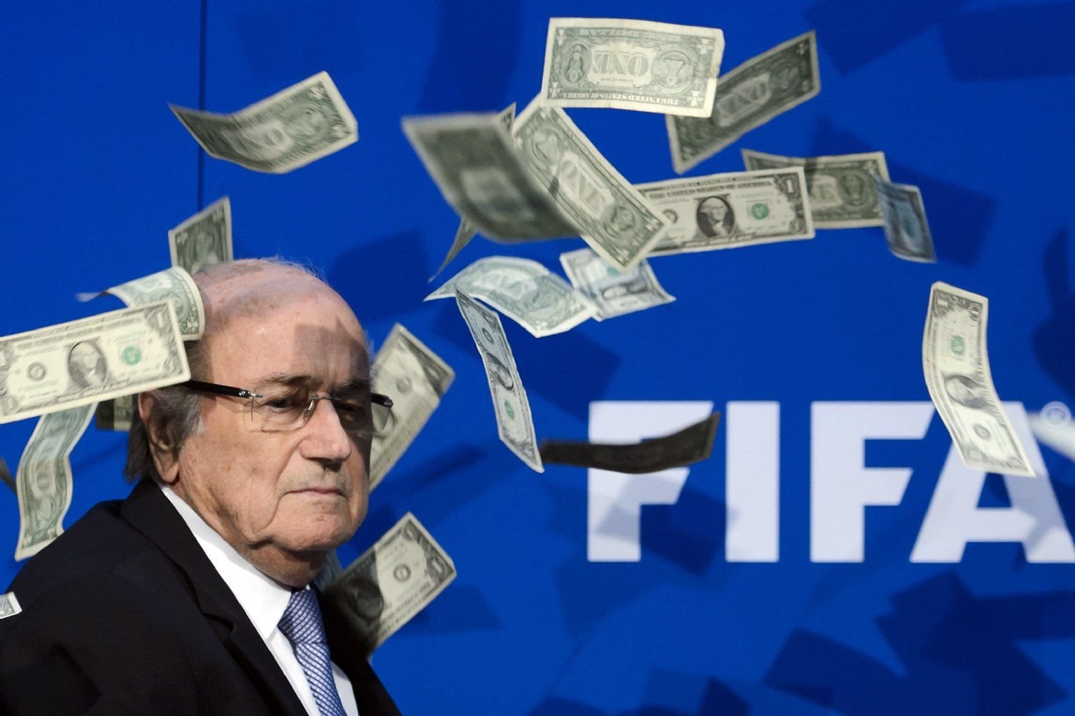 Dollar-Noten regnen auf den FIFA-Präsidenten Sepp Blatter hinab.