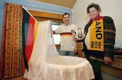 Mit Fußballfan-Utensilien präsentieren sich Frank Schäffer (l.) und Anja Ackermann vor der noch leeren Kinderwiege in ihrem Haus im nordhessischen Lohfelden (Foto vom 06.02.2007). Neun Monate nach der Fußball-Weltmeisterschaft kündigt sich für Deutschland ein kleiner Babyboom an. Auch das Paar aus Nordhessen erwartet ziemlich genau neun Monate nach dem Endspiel in Berlin Nachwuchs. (Foto: dpa)