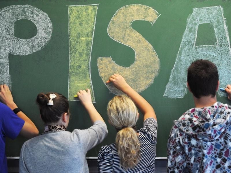 Schüler der malen in einem Gymnasium in Straubing (Niederbayern) das Wort „PISA” auf eine Tafel. Foto: Armin Weigel/dpa